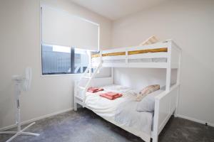 a white bunk bed in a white room with a window at Stylish 4BR Home, Netflix, Walk to Eateries and Schools in Auckland