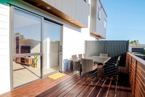a patio with a table and chairs on a deck at Stylish 4BR Home, Netflix, Walk to Eateries and Schools in Auckland