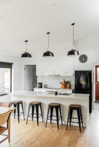 a kitchen with white cabinets and a large island with stools at Jimmara House Modern central holiday home in Halls Gap +19 photos