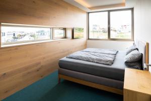 a small bedroom with a bed and two windows at LAKESIDE Apartements in Zwenkau