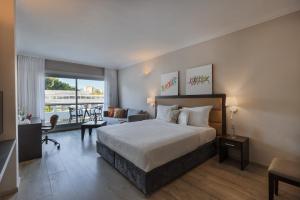 a hotel room with a bed and a balcony at Kfar Maccabiah Business & Sport Hotel in Ramat Gan