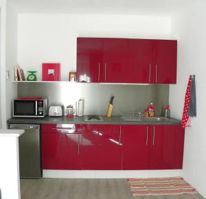 a kitchen with red cabinets and a microwave at Provencal Vintage Cocoon in L'Isle-sur-la-Sorgue