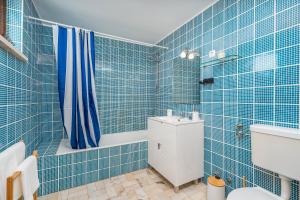 a blue tiled bathroom with a toilet and a sink at Gaivotas House in Alvor +19 photos