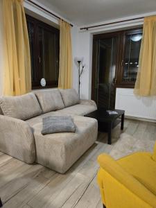 a living room with a couch and yellow curtains at TATRYSTAY Apartment Granit 104 in Tatranská Lomnica