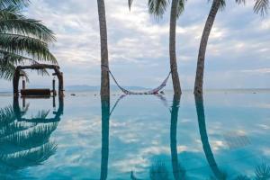 通萨拉Yiuvilla Luxury Beachfront Villa Koh Phangan的一座拥有棕榈树和吊床的游泳池