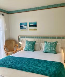 a bed with green and white sheets and pillows at Hotel des Dunes in Cap-Ferret