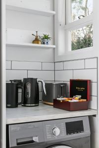 a kitchen counter with two coffee pots and a microwave at Garden Oasis - 5min walk to CBD in Gisborne +16 photos