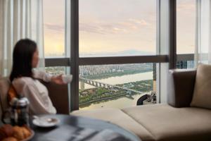 a woman holding a cup of coffee in front of a window at Grand Hyatt Changsha in Changsha