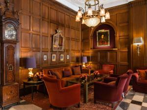 a living room with a couch and chairs and a clock at Fairmont Hotel Vier Jahreszeiten in Hamburg