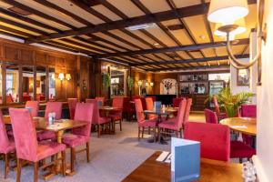 a dining room with tables and red chairs at Roebuck by Greene King Inns in Forest Row