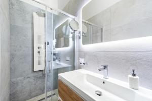 a white bathroom with a sink and a mirror at Hotel Dua Residence in Poreč