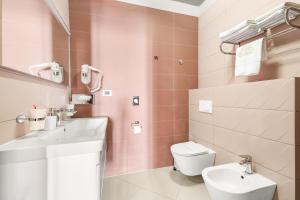 a pink bathroom with a sink and a toilet at Hotel Dua Residence in Poreč