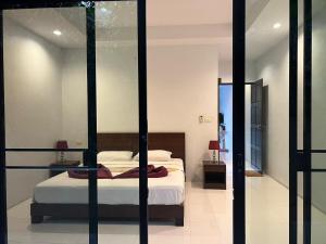 a bedroom with a bed and a glass wall at Nern Khao Guest House in Kamala Beach