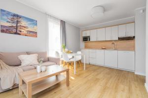 a kitchen and living room with a couch and a table at APARTAMENTY MIERZEJA - STEGNA FOREST, Przyjazne Zwierzętom, Blisko Lasu, Bezpłatny Meleks in Stegna