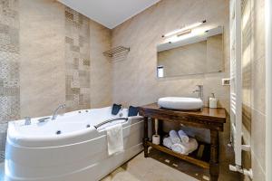 a bathroom with a tub and a sink and a mirror at Yael Luxury Apartments 2 in Buşteni +99 photos