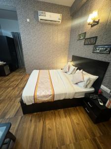 a bedroom with a large bed with a wooden floor at Garnet suites at omaxe enternity in Chhatikara