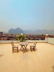 a patio with two chairs and a table on a roof at T N A Hotel in Vang Vieng +18 photos