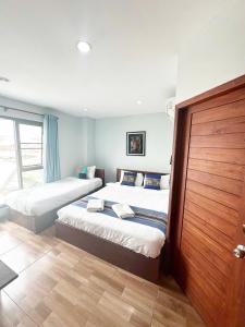 a bedroom with two beds and a wooden door at T N A Hotel in Vang Vieng