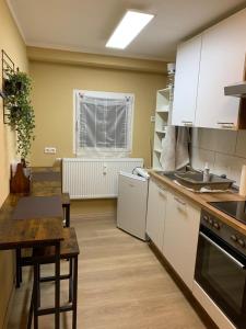a kitchen with white cabinets and a table and a sink at Gemütliches Apartment in Bodenfelde in Bodenfelde +6 photos