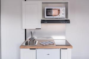a kitchen with a sink and a microwave at Solaria - Logement Climatisée à Jean Jaurès in Toulouse