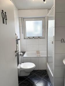 a bathroom with a toilet and a tub and a window at Große 6 Personen Wohnung I Balkon I zentral I Boxspringbett I Wifi in Hamm +11 photos