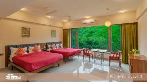 two beds in a room with a large window at Lilly Valley Villa In Lonavala in Lonavala
