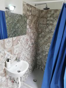 a bathroom with a sink and a shower with blue curtains at Casa Bonita Pachino in Pachino +28 photos