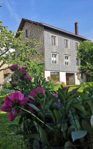 uma casa com flores roxas na frente em GITE DE MONTAGNE "LE CALOU" AVEC CHEMINEE ET JACUZZI situé à St Laurent-en-Grandvaux em Saint-Laurent-en-Grandvaux mais 20 fotografias
