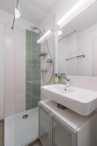 Un baño blanco con lavabo y ducha. en Wine & Four - Chambre Agréable sur les Allées, en Toulouse