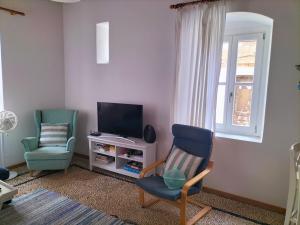 a living room with two chairs and a television at Alexandros Traditional House in Ialysos