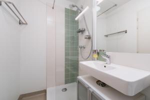 Un baño blanco con lavabo y ducha. en Aube Cachée - Chambre Calme au Coeur de Toulouse, en Toulouse