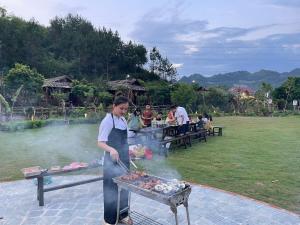 une femme fait cuire des aliments sur un gril dans l'établissement Natalie's Villa & Resort Moc Chau, à Mộc Châu