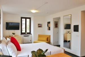 a bedroom with a white bed and a television at Studio Red - by MyHomeInComo in Argegno