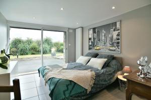 a bedroom with a bed and a large window at Chez Marie-Céline - Maison avec jacuzzi à 20 min du Val André in Plestan