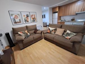 a living room with a brown couch and a kitchen at Apartamento San Andrés in Teruel