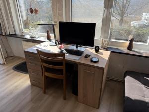 a desk with a computer on it in a room with windows at Ferienhaus Stausee Bitburg in Biersdorf am See