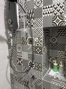 a shower with black and white tiles on a wall at HomeSweetHome Alinea Suites Shah Alam in Shah Alam