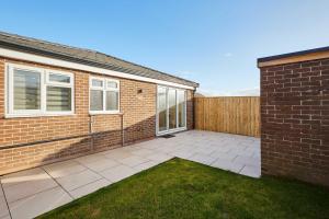 a brick house with a patio and a fence at Host & Stay - Middle Cottage in Seahouses