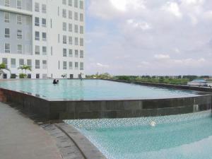 a large swimming pool in front of a building at Cozy Stay and Tranquil Studio Patraland Urbano Apartment By Travelio in Bekasi