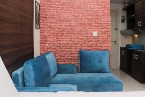 a blue couch in front of a brick wall at Cozy Stay and Tranquil Studio Patraland Urbano Apartment By Travelio in Bekasi