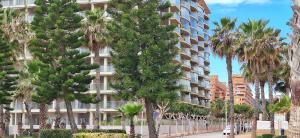 a building with palm trees in front of a street at Marina d'Or Edificio Fase X - 1ª linea apartment in El Borseral