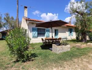 a table with an umbrella in front of a house at Charmante maison en Camargue avec piscine partagée in Saintes-Maries-de-la-Mer