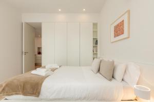 a white bedroom with a large bed with white pillows at Boavista Collection Apartment by Sé Apartamentos in Braga