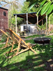 una panca di legno seduta sull'erba accanto a una griglia di temps 1solite a Andenne