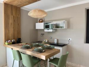 cocina con mesa de madera y sillas verdes en Mandalay Lodge & Resort Senigallia, en Senigallia