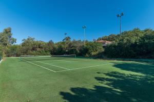 een tennisbaan met een net op een groen veld bij Le Dalie With Shared Pool - Happy Rentals in Marinella