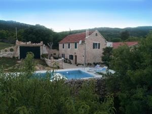 a stone house with a swimming pool in front of it at Holiday Home Leptir in Drniš