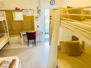 a room with bunk beds and a table and a desk at Dar Yasmine in Pantai Cenang
