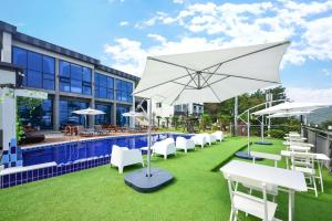 a group of white chairs and an umbrella next to a pool at Yeosu Tivoli Pension in Yeosu
