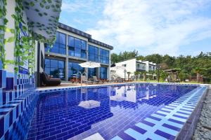 a swimming pool with blue tiles on the side of a building at Yeosu Tivoli Pension in Yeosu